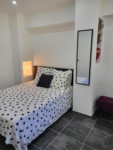 a bedroom with a black and white bed with a mirror at Appart Allée des chênes in Furiani