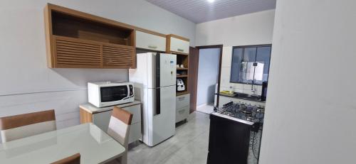 a kitchen with a white refrigerator and a microwave at Casa 2 quartos, Pet Friendly, 06 pessoas Sinop in Sinop