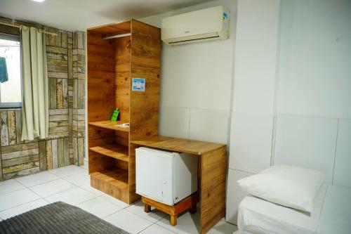 a small room with a bed and a small refrigerator at Pousada vila bela in Porto De Galinhas