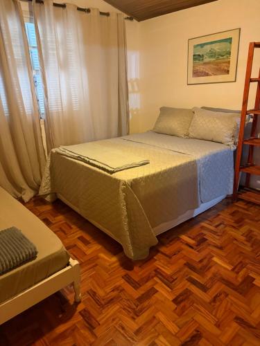 a bedroom with a bed and a wooden floor at Do Sítio Tinoca in Atibaia
