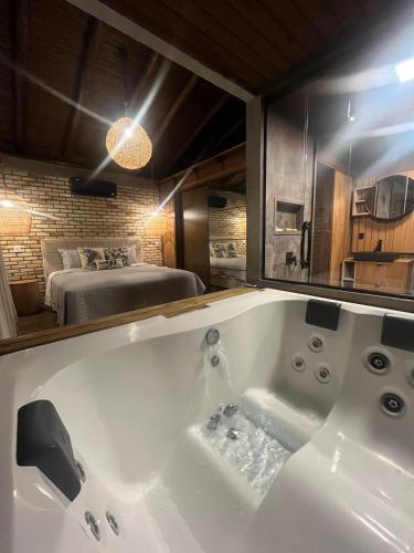 a bathroom with a tub and a bed in a room at Luz de Arcturus, Chalé com jacuzzi aquecida in Imbituba