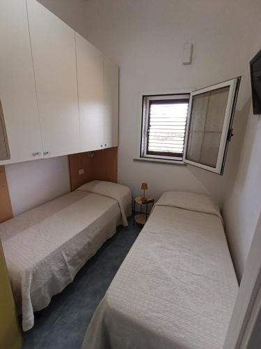 two beds in a small room with a window at Casa Orchidea in Villasimius