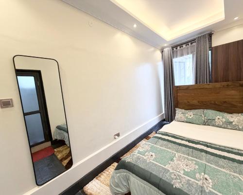 a bedroom with a bed and a mirror at Perfect Homes Namugongo in Kasiyirize