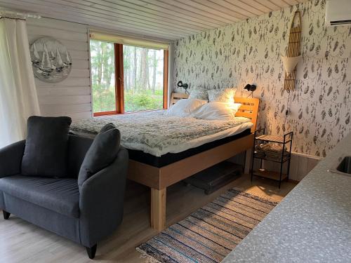 a bedroom with a bed and a couch and a window at sun& relax- TINYHOUSE in Sõitme