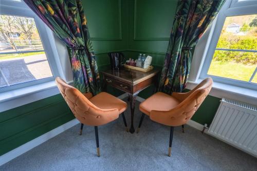 a desk and two chairs in a room with windows at Casa Sona in Spean Bridge