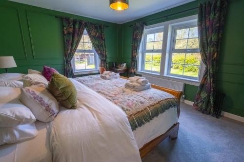 a green bedroom with two beds and two windows at Casa Sona in Spean Bridge