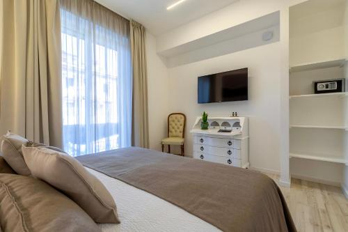 a bedroom with a bed and a tv and a window at RelaisApartments PORTO in Alghero