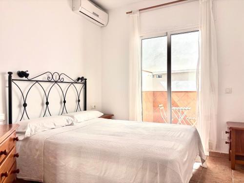 a white bedroom with a bed and a window at Easy Nerja Apartments in Nerja