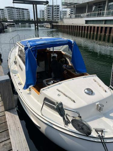 a white boat tied to a dock with a blue canopy at Romantisk båd nær Kbh in Copenhagen