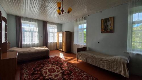 a bedroom with two beds and windows and a rug at Vamesa in Haghpat