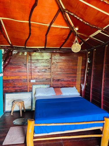 a bed in a room with a wooden wall at Eco Tree House Yala in Tissamaharama