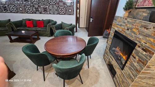 a living room with a fireplace and a table and chairs at Alpin Aparthotel Ap 508 Poiana Brasov- acces la piscină gratuit in Poiana Brasov