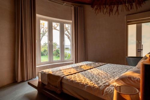a bedroom with a bed and a large window at QUEEN VILLA - Hoa Tiên paradise in Ðông Hội