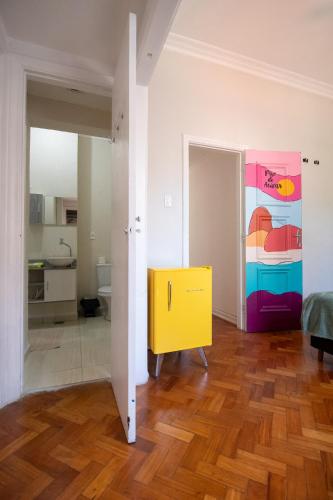 a living room with a yellow cabinet and a painting on the wall at Maroca RIO in Rio de Janeiro