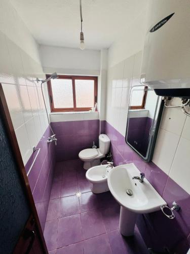 a purple and white bathroom with two toilets and a sink at Cozy Pogradec in Pogradec