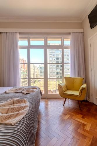 a bedroom with a yellow chair and a large window at Maroca RIO in Rio de Janeiro