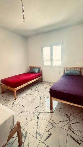 two beds in a room with a marble floor at Appartements de rêve in Hennchir Ksar Rhaleb