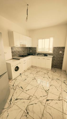 a kitchen with white cabinets and a marble floor at Appartements de rêve in Hennchir Ksar Rhaleb