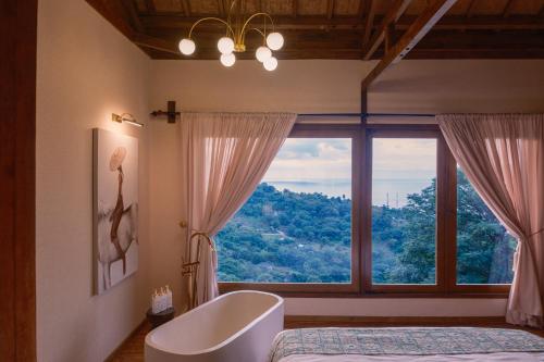 a bathroom with a tub and a large window at Villa Layan Hillside Residency with views and infinity pool in Amed in Ambat
