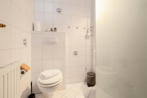 a white bathroom with a toilet and a shower at Strandläufer in Thiessow