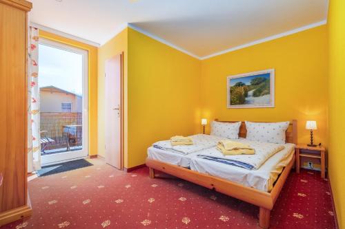 a yellow bedroom with a bed and a window at Muschelbank in Thiessow