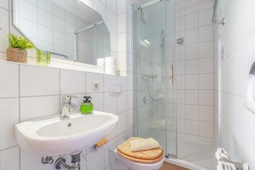 a white bathroom with a sink and a shower at Muschelbank in Thiessow