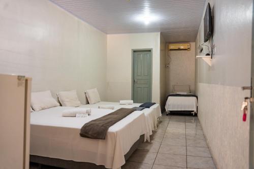 a hotel room with three beds and a television at Porto Seguro Hotel - Porto Velho in Porto Velho