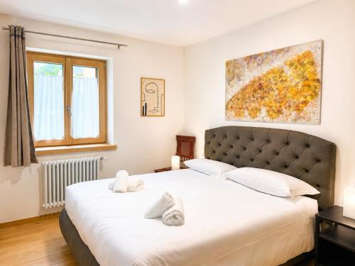 a bedroom with a large bed with white sheets at Rosso Betulle, Free Park and Ski room in Camporosso in Valcanale