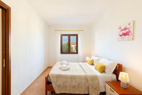 a white bedroom with a bed with a window at Molara Ichnos House in San Teodoro