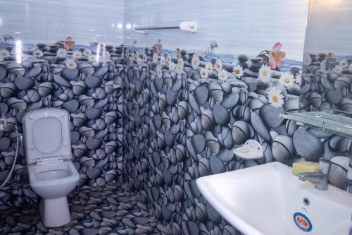 a bathroom with a wall of rocks and a toilet at minidu resort in Ambalantota