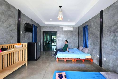 a person sitting on a bed in a bedroom at มีดี ฟาร์ม โฮมสเตย์ in Ban Klam