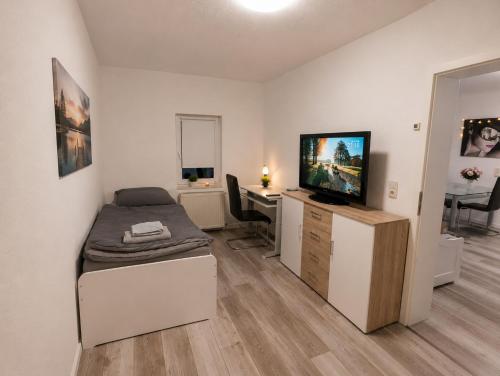 a room with a bed and a desk with a flat screen tv at Mitarbeiterwohnung nahe Saaleck Kaserne in Hammelburg