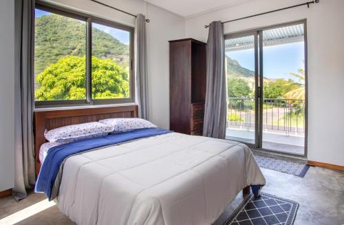 a bedroom with a bed and a large window at Le Morne Base - Stylish, Pool & Rooftop in La Gaulette