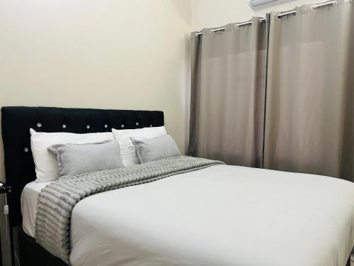 a white bed with a black headboard and white pillows at Brilliant Home in Gaborone