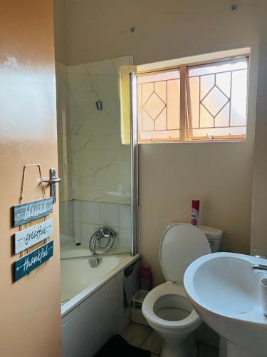 a bathroom with a toilet and a sink and a shower at Brilliant Home in Gaborone