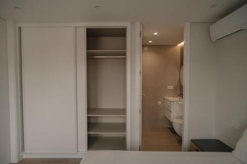 a bedroom with a door to a closet with a toilet at Alba Esposende - Balcony Apartment in Esposende