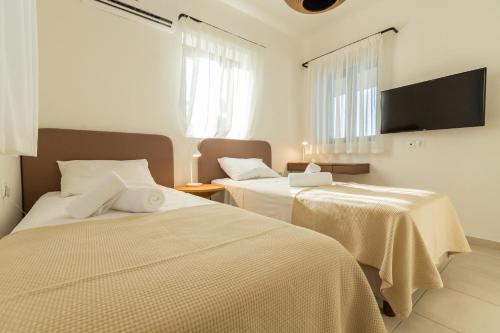 a bedroom with two beds and a flat screen tv at Villa Metochi in Skala