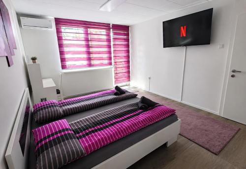 a room with a bed with purple sheets and a tv at Stan na dan Bosanska Krupa in Bosanska Krupa