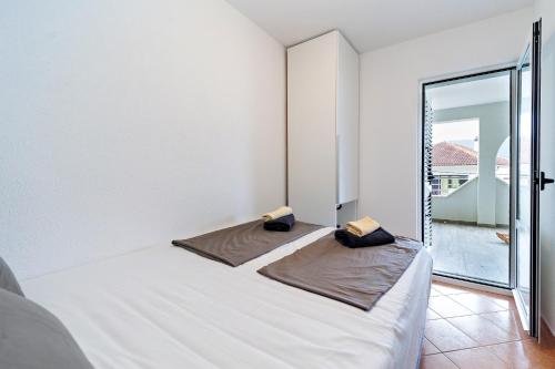 a white bedroom with a bed and a balcony at Dzon Beachside Apartments in Vinišće