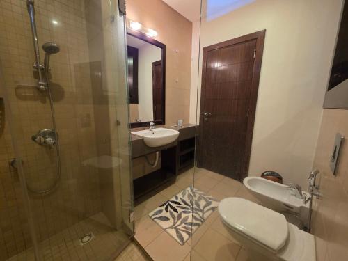 a bathroom with a shower and a toilet and a sink at Spacious Abdoun 2BR with private garden & pool access in Amman