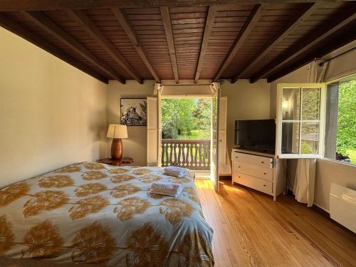 a bedroom with a large bed and a television at La dépendance in Luchon