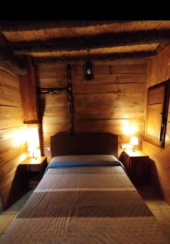 a bed in a wooden room with two night lights at Casa Sabinar in Navajas
