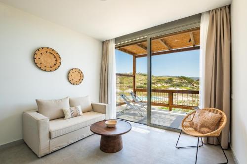 a living room with a couch and a balcony at Ramnus Karpathos Suites in Karpathos
