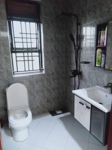 a bathroom with a toilet and a sink and a window at Sunset Grove in Pakwach East