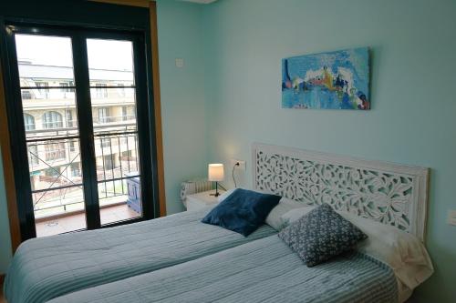 a bedroom with a bed with a large window at PLAYASDEBARREIROs in San Miguel de Reinante