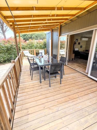 a wooden deck with a table and chairs on it at Mobil Home - 3CH - 2 SDB - Clim - Wifi in Roquebrune-sur-Argens