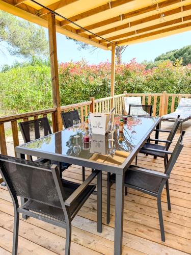 a dining table and chairs on a deck at Mobil Home - 3CH - 2 SDB - Clim - Wifi in Roquebrune-sur-Argens