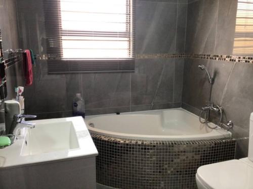 a bathroom with a tub and a sink and a toilet at Private Secure house in Alberton in Alberton