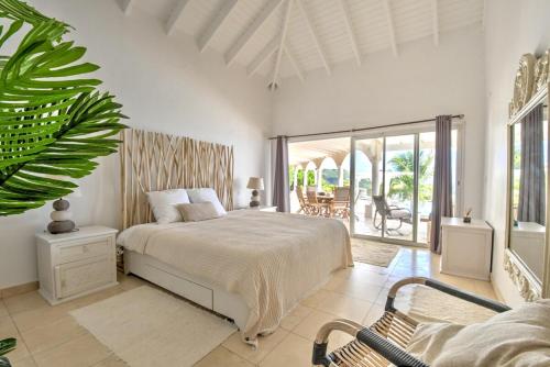 a white bedroom with a bed and a balcony at villa coralia - panoramic view in Saint Martin