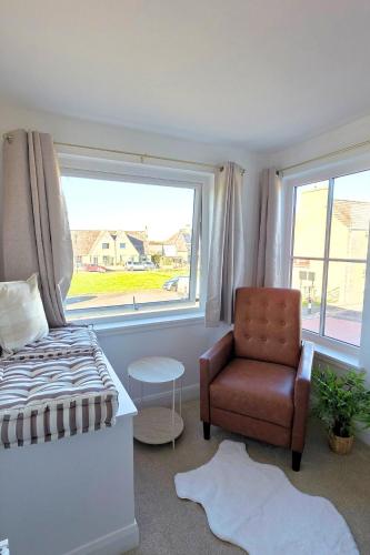a bedroom with a bed and a chair and a window at Coastal Cottage NC500 in Castletown